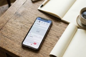 Смартфон с лентой соцсети, блокнот и монеты на рабочем столе
