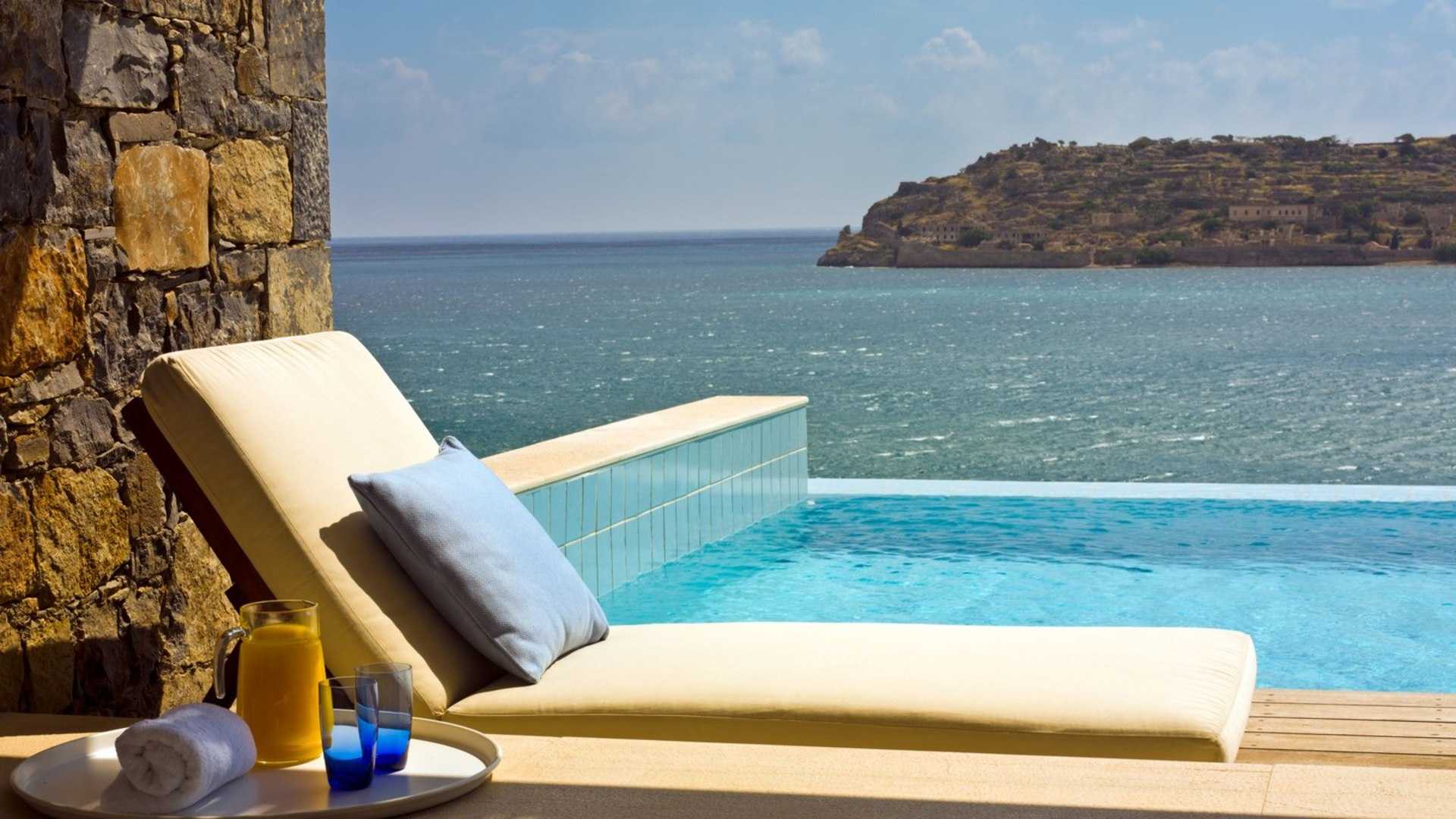 Отели рядом с морем. Blue Palace, a Luxury collection Resort and Spa, Crete 5*. Шезлонг на море. Бассейн на берегу моря. Шезлонг на берегу моря.